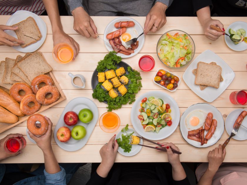 Enjoying dinner with friends.  Top view of group of people having dinner together while sitting at wooden table