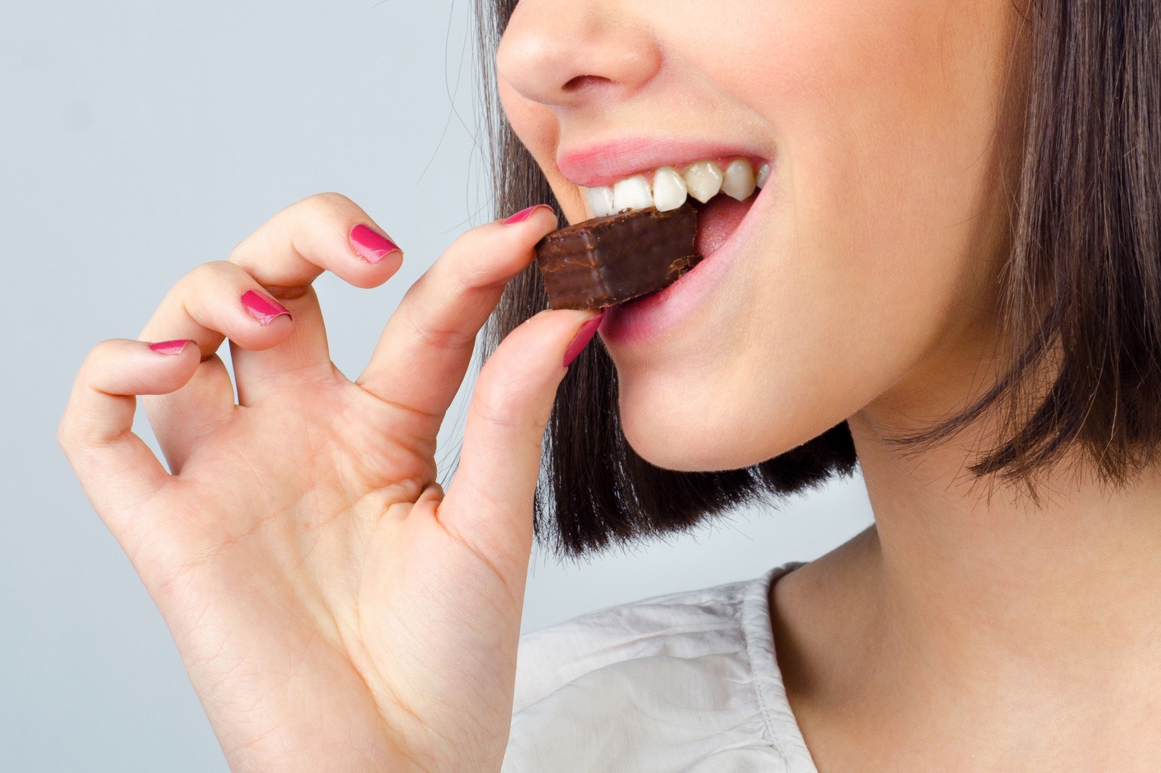 Portrait of the beautiful girl eating chocolate cookies isolated